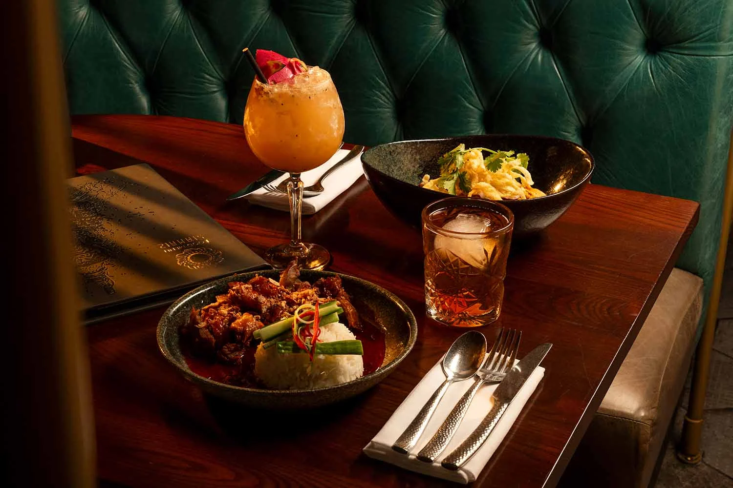Cocktails and Thai dishes on a booth table at Siamais
