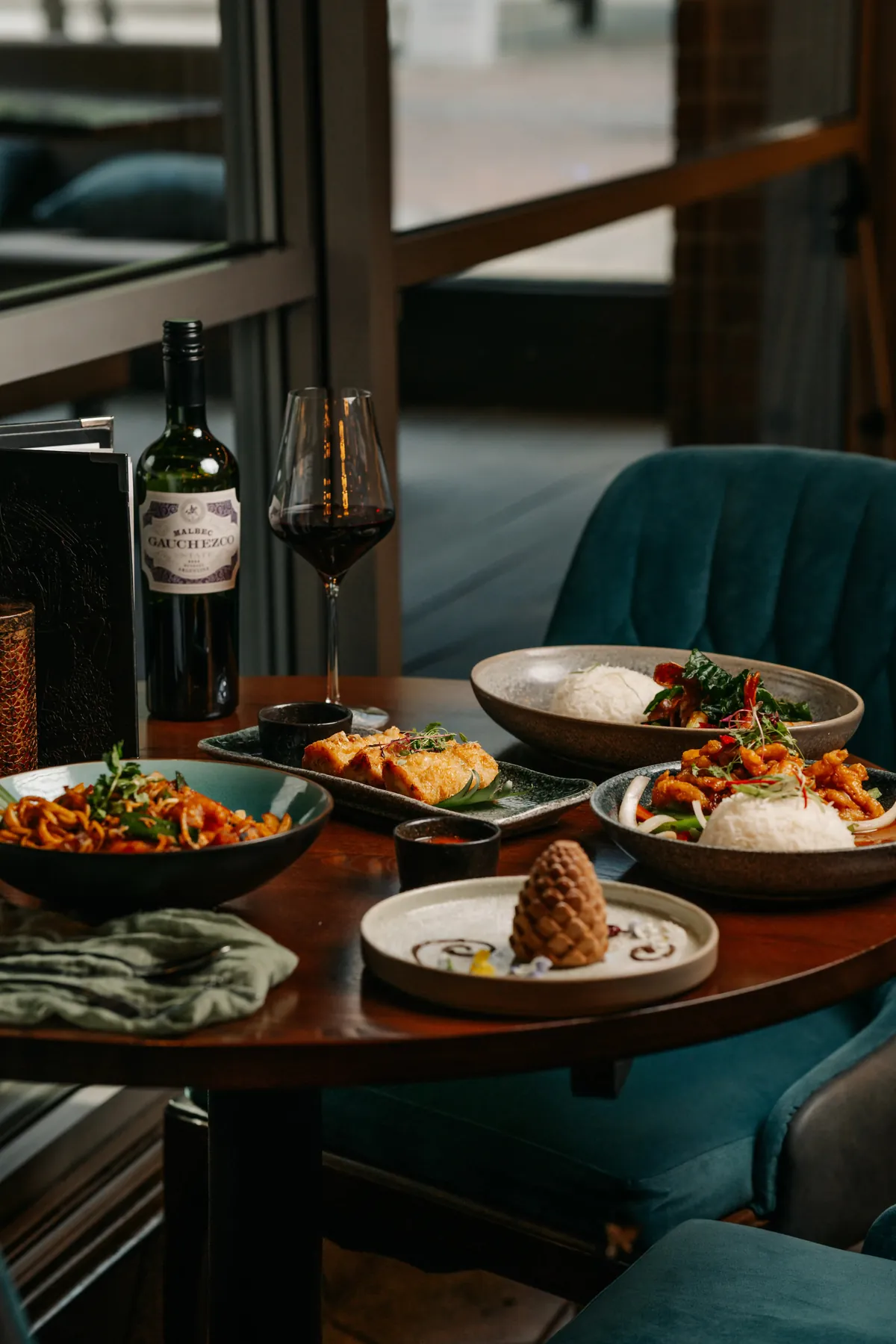 A table set with Thai sharing dishes and wine for a party at Siamais